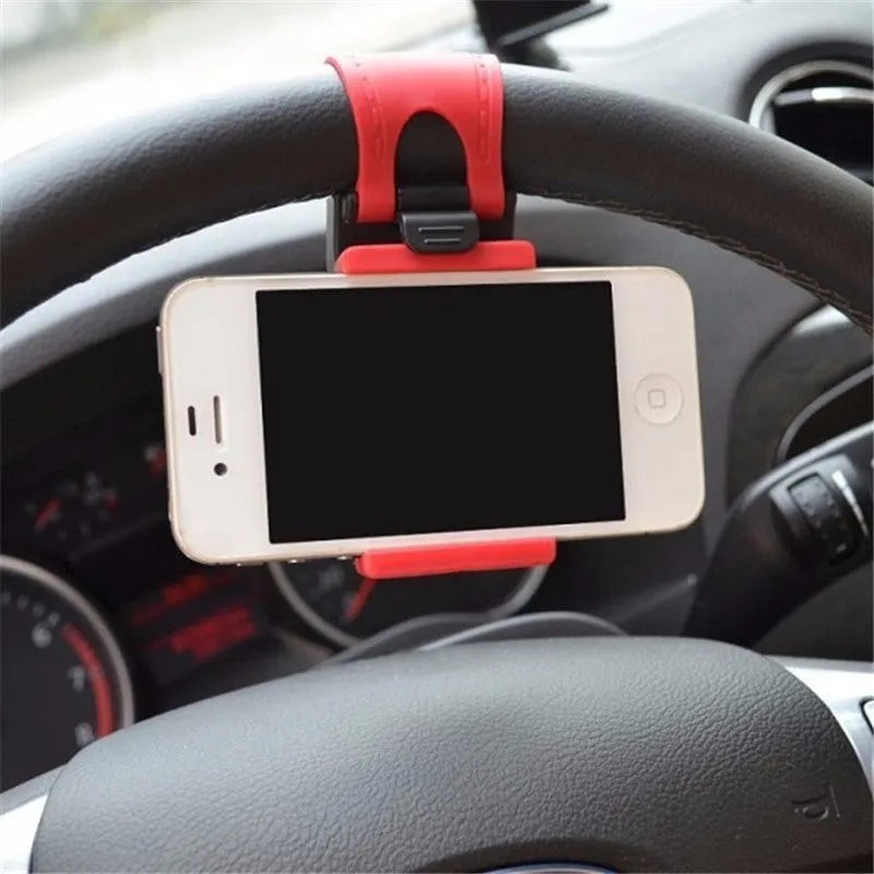 Black steering wheel phone mount holder clipped to a car wheel, holding a large smartphone.