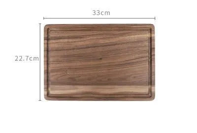 Black walnut wood chopping board with juice groove and side handle on kitchen counter