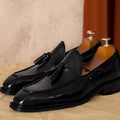 Men's black genuine leather slip-on loafers with fringe detail and rubber sole.