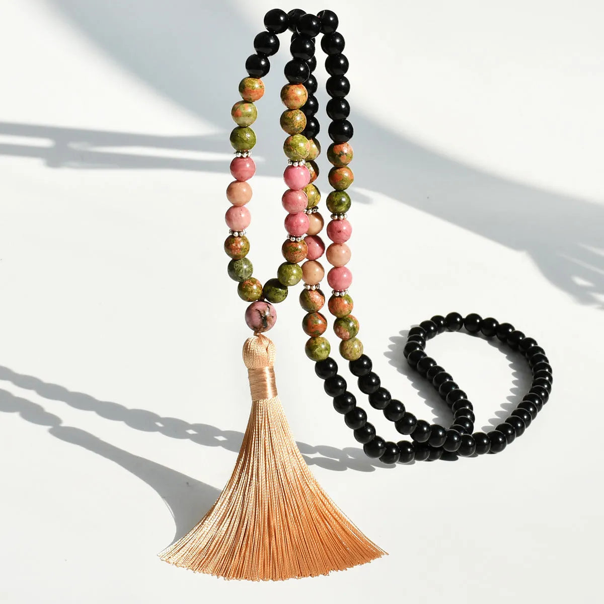 Long 108-bead natural stone necklace with colour-matched tassels and a geometric gem-inlaid pendant on a ball bead chain.