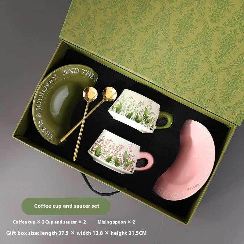 Ceramic coffee cup and saucer set for two people with stirring spoons.