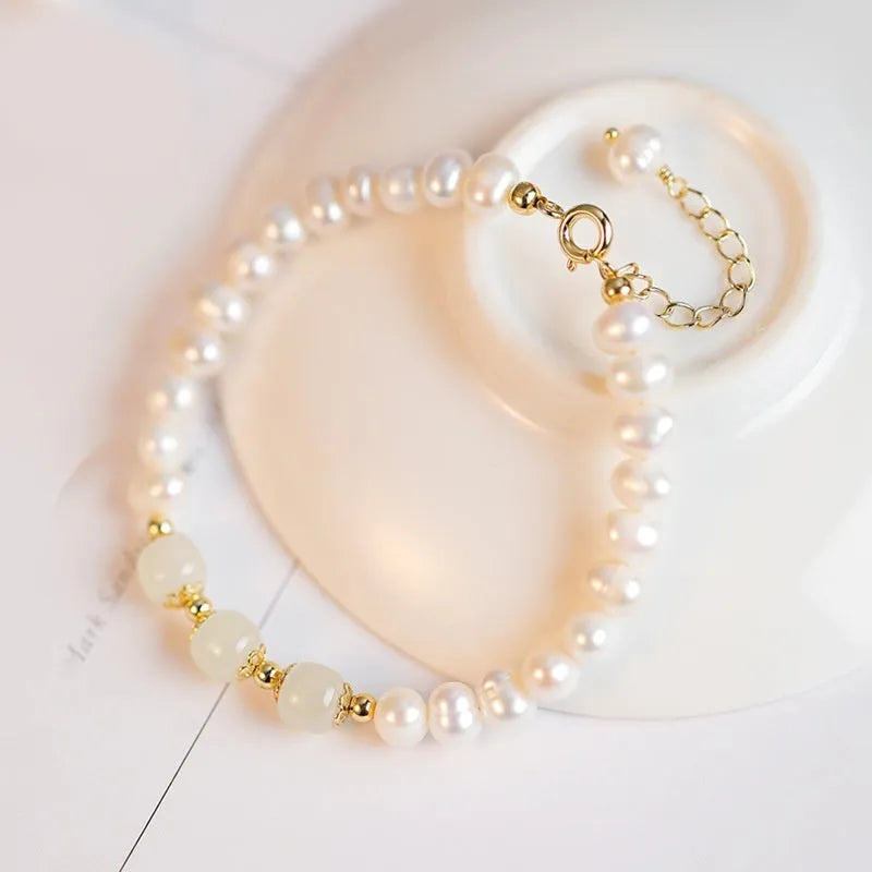 Natural freshwater pearl bracelet with diamond-shaped beads in Hetian jade colour on a wrist.