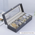 Grey leather watch storage box with transparent lid showing multiple watch slots inside.