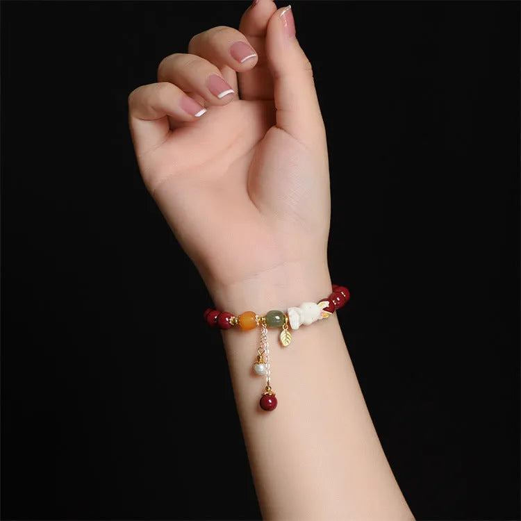 Natural cinnabar bracelet with hand-carved rabbit charm and metallic accents in deep purple-red colour
