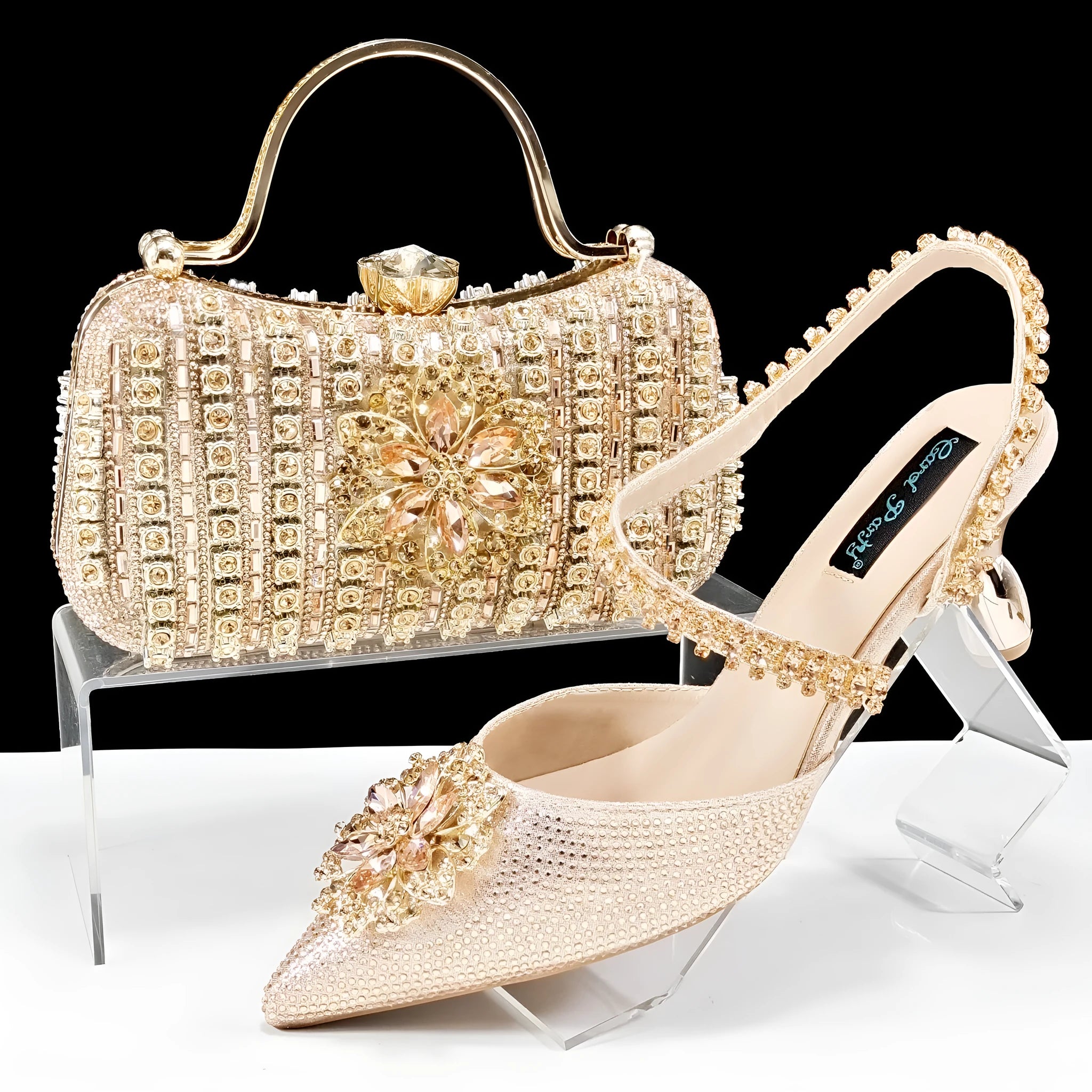 Women's black high heel ankle-strap sandals with floral buckle and chain detail next to matching clutch bag
