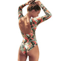 Women's one-piece swimsuit with green leaf print on a dark background, conservative cut.