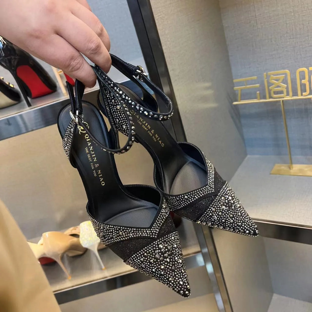 Women's black hollow high heels with red sole and stiletto heel on a plain background.