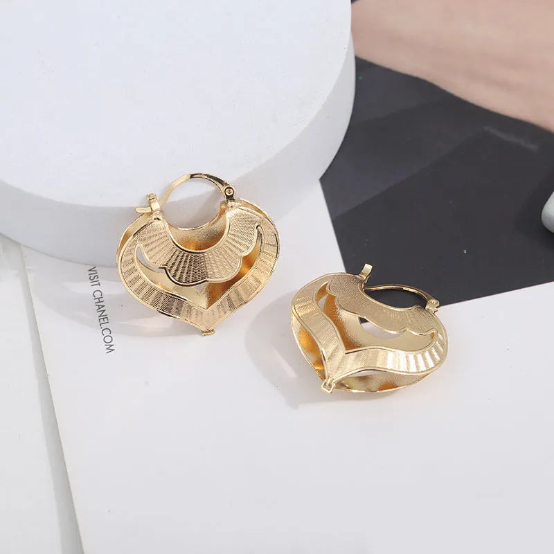 Gold electroplated copper heart-shaped hollow stud earrings with lace-inspired openwork design and geometric round elements