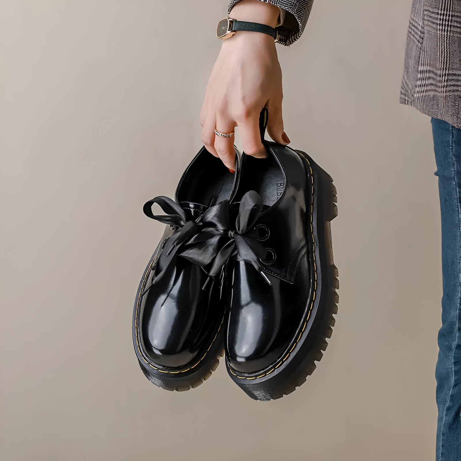 Black thick soled women's lace-up shoes with ribbon and cross strap details on a white background.