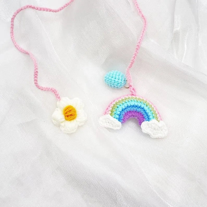Handmade crocheted car pendant featuring a colourful avocado and rainbow flower design in wool yarn.