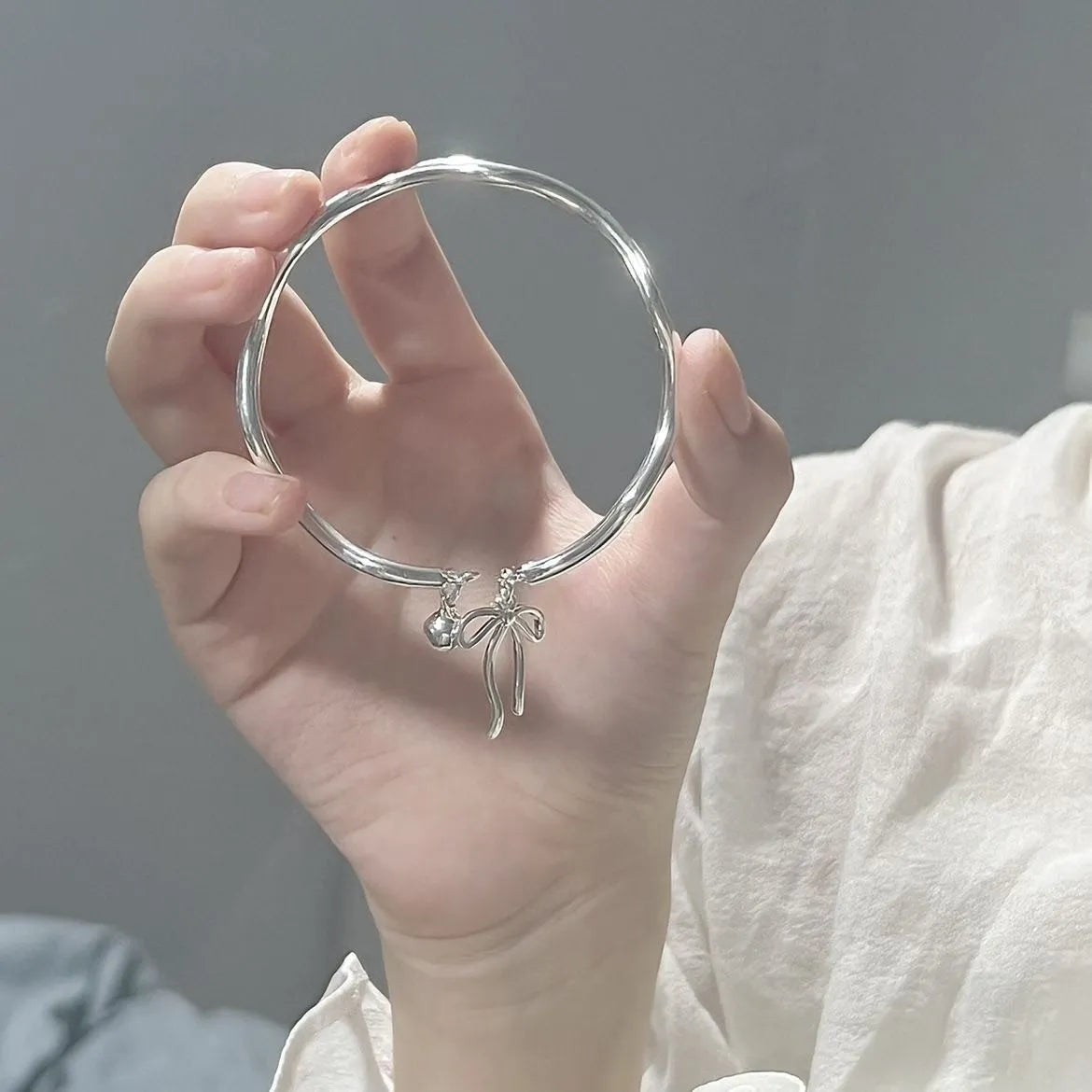 Silver adjustable bracelet with bow charm and opening bell clasp