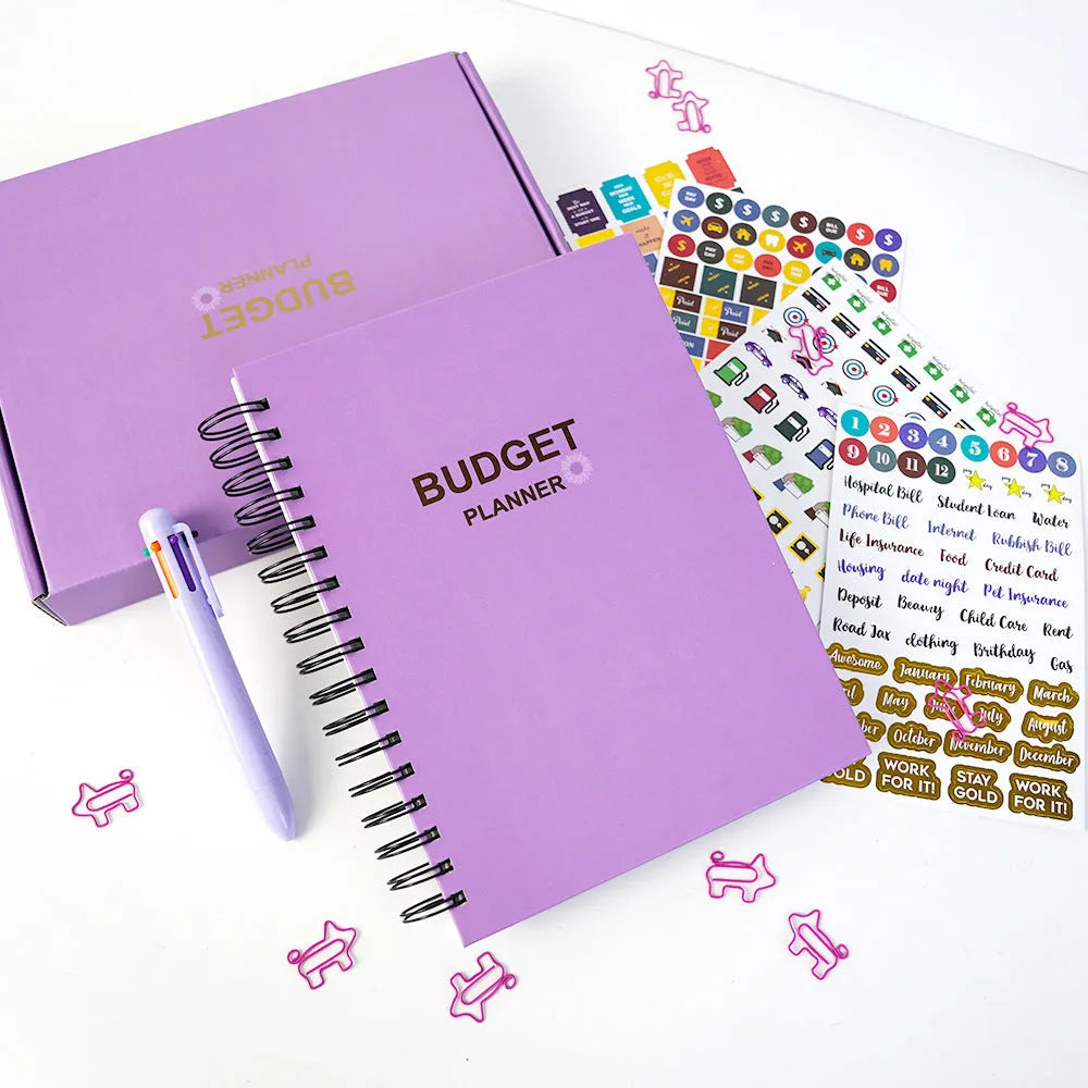 Purple coil-bound budget notebook with pen and stickers for financial planning