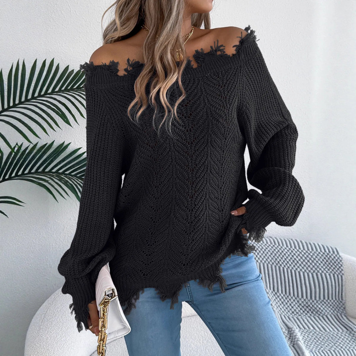 White hollow-out off-the-shoulder long-sleeve pullover sweater laid flat.
