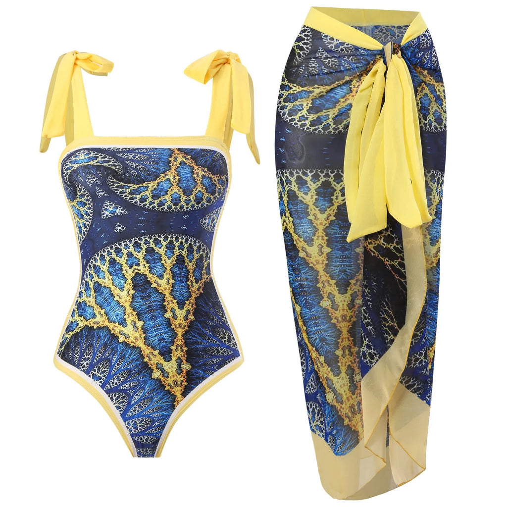Yellow retro one-piece swimsuit with floral print and a sheer black chiffon skirt.