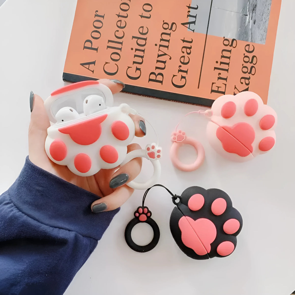 Cat's paw silicone earphone case for Apple AirPods, cute cartoon design, available in black, pink, or white.