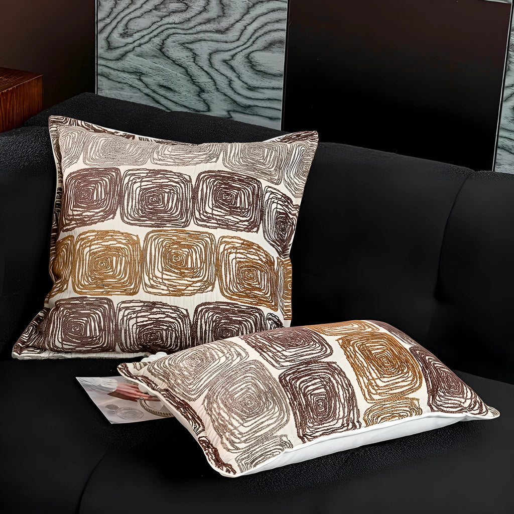 Square and rectangular decorative cushion covers with an abstract coil pattern in cream and coffee brown colours.
