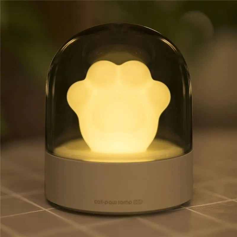 Grey and pink cat paw shaped night light with USB charging cable and musical rotation feature