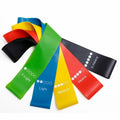 Five yoga stretching bands in different colours showing graduated thickness for progressive resistance training