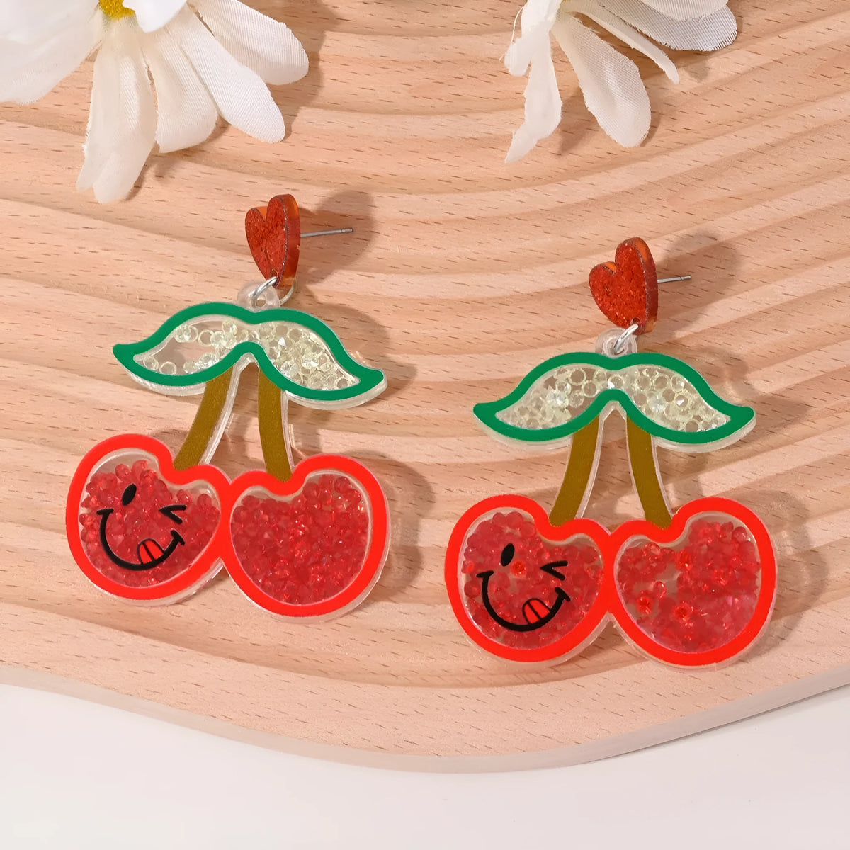 Acrylic drop earrings shaped like a strawberry, cherry, watermelon, pineapple, cake, ice cream, and coconut tree on a white background.