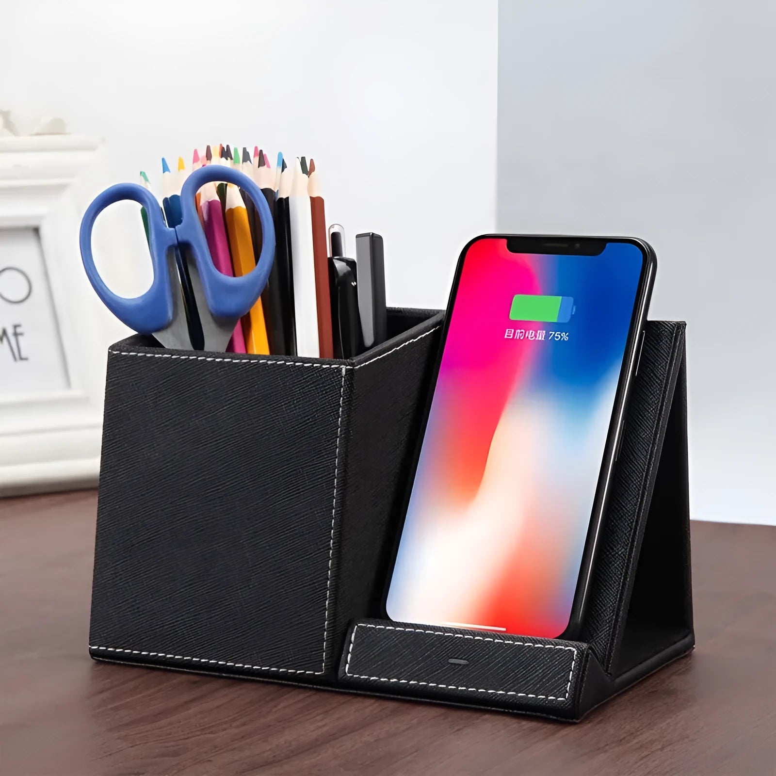 Black leather wireless charging station with pen holder slots showing phone charging on surface