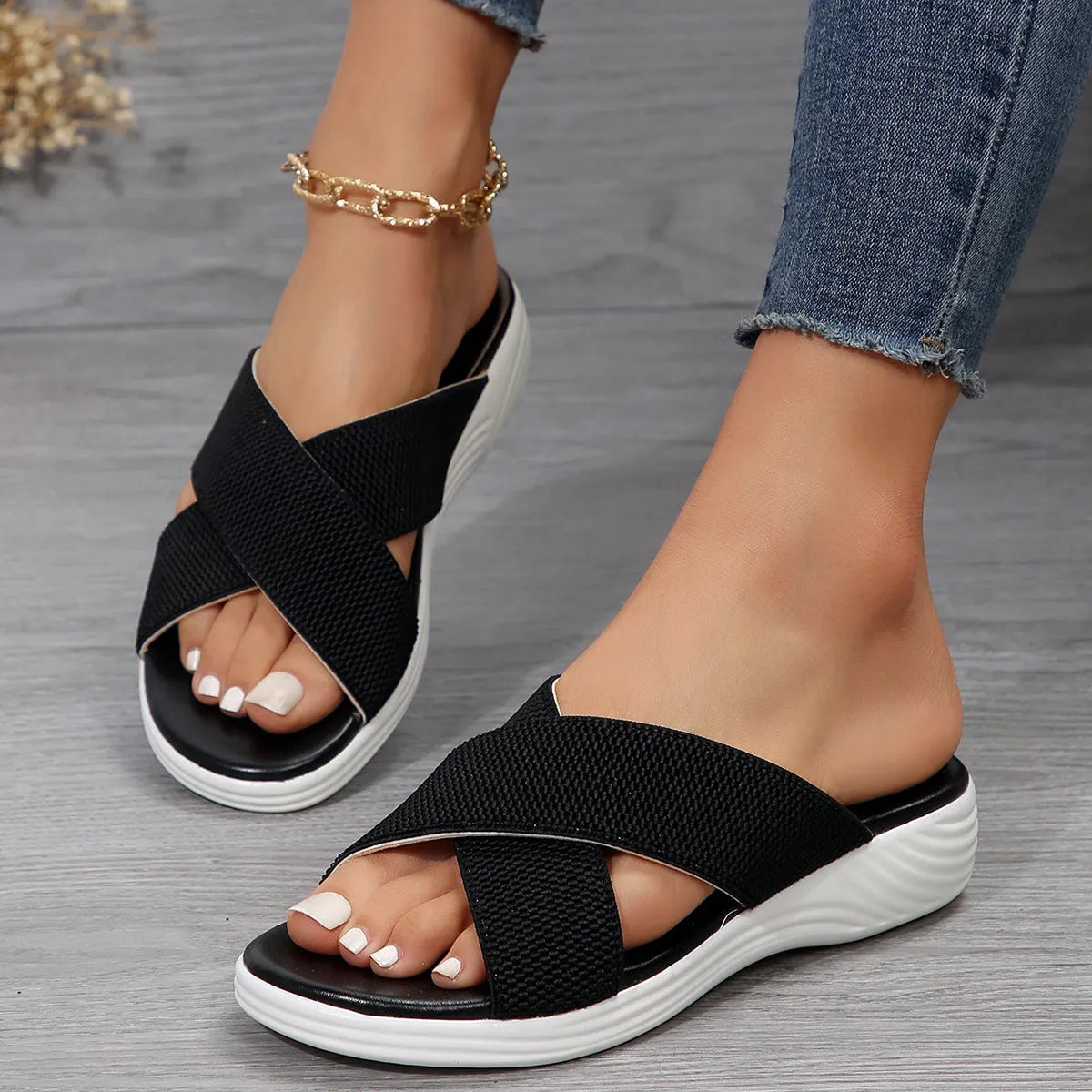 Black wedge slippers with peep toe and thick rubber sole on a grey background.