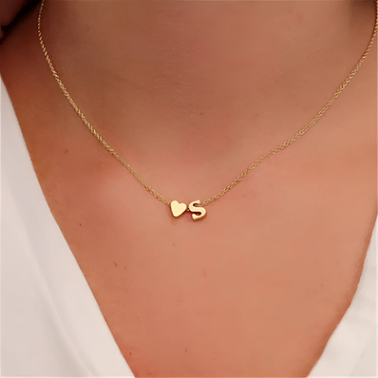 Gold heart shaped alloy pendant with initial letter on white background