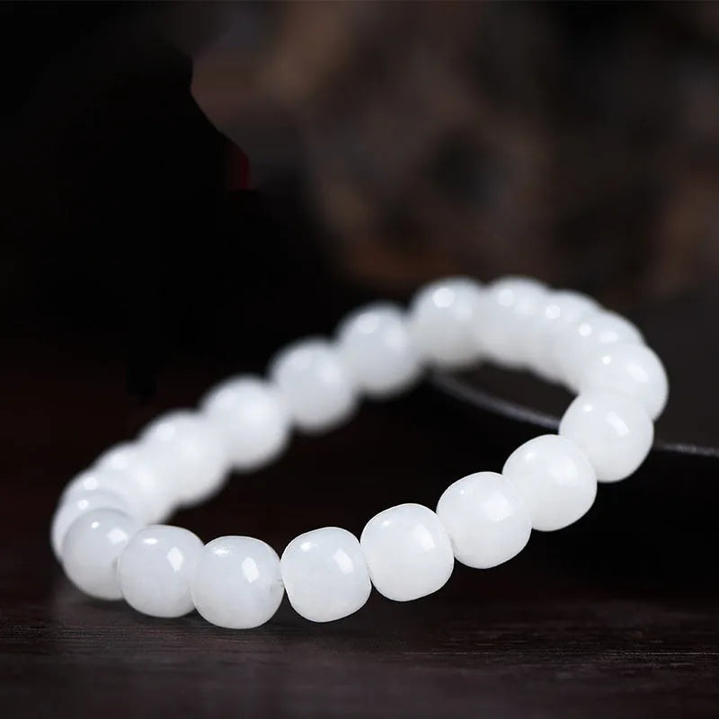 White Hetian jade barrel bead bracelet on a wrist, showing smooth beads in a unisex casual style.