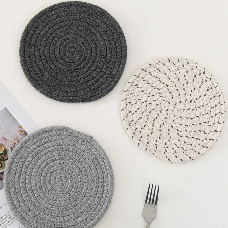 Three round cotton cord coasters in coordinating colours on wooden table