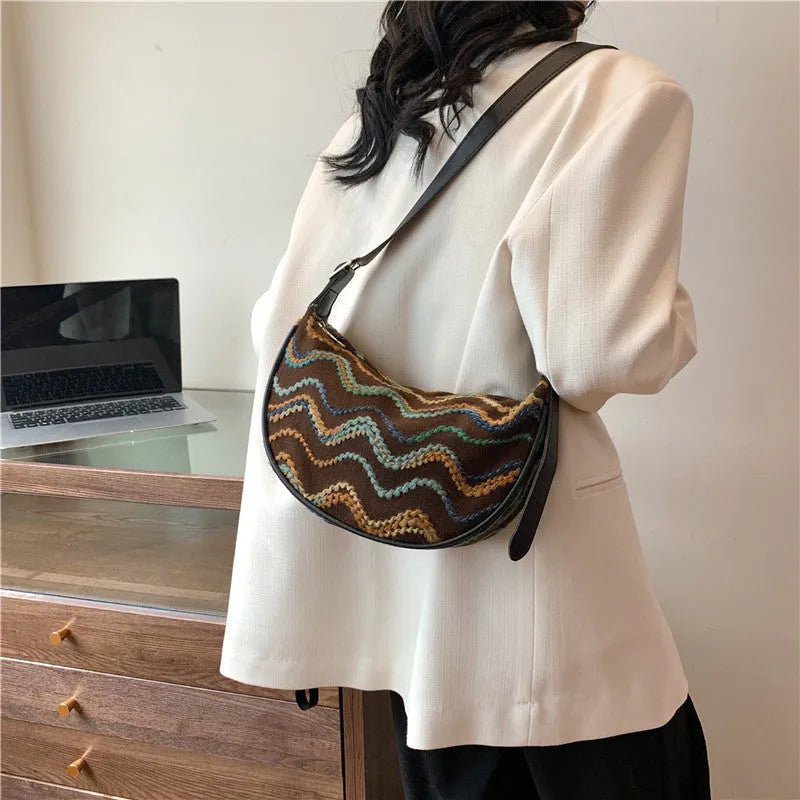 Women's woven straw crossbody bag with a single strap and internal organisation pockets.