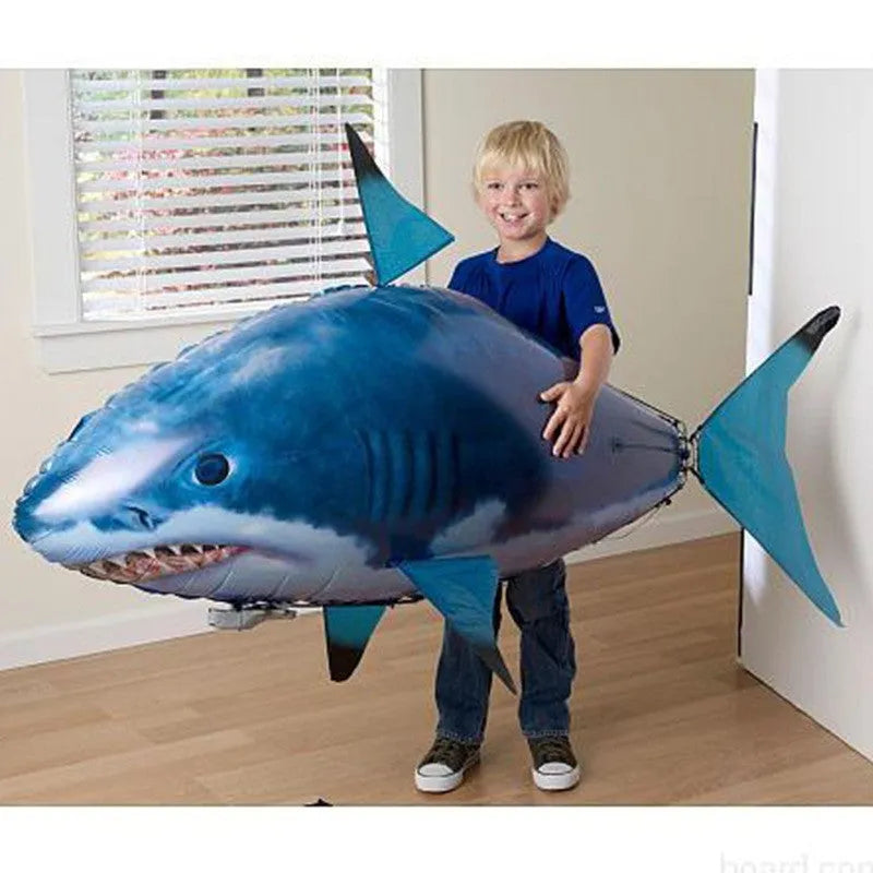 Large remote control inflatable shark balloon toy floating indoors with remote controller.