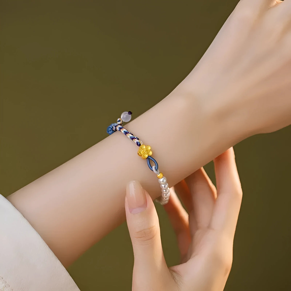 Peach-coloured adjustable cord bracelet with Chinese flower weaving and pearl details.