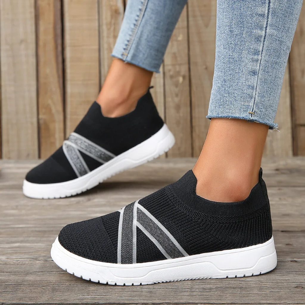 Black women's flat shoes with flyknit mesh upper, round toe, tassel detail, and rubber sole.