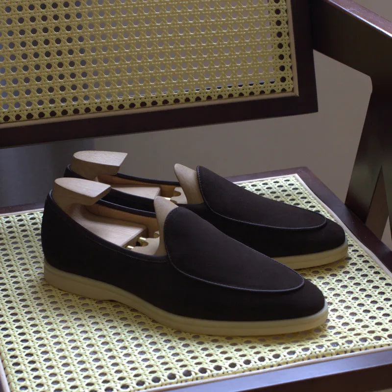 British handmade men's brown genuine leather flat loafers on a plain background.