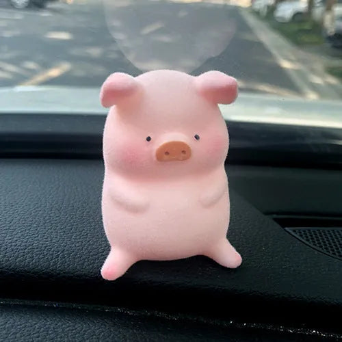 A cute resin cartoon pig figurine car dashboard decoration on a grey background.