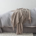 Small light grey polyester fibre blanket measuring 127 by 170 centimetres, folded on a sofa.