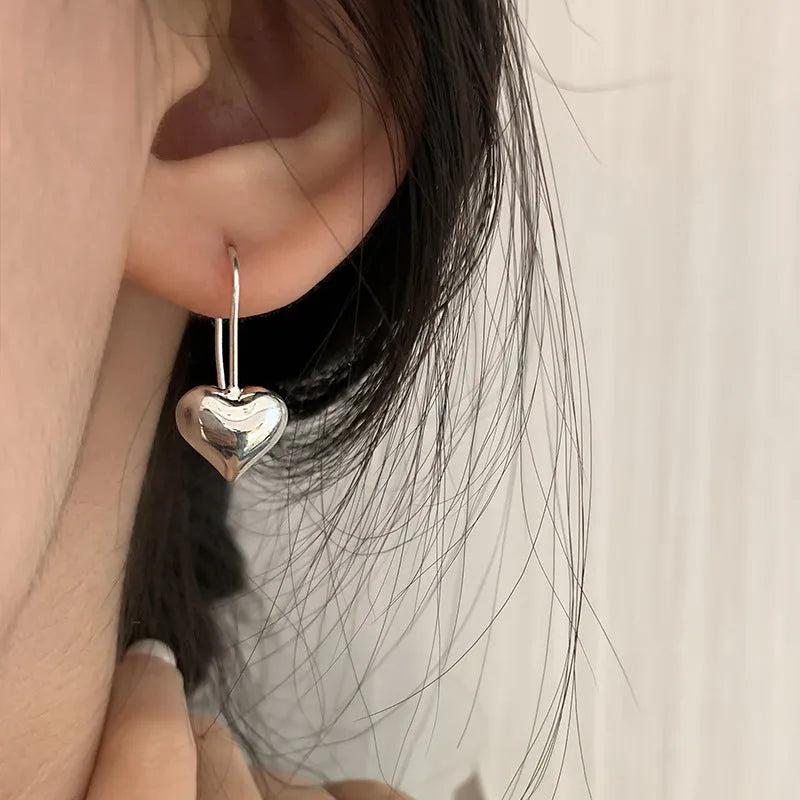 Silver heart-shaped earrings with glossy finish and three-dimensional Korean-style design