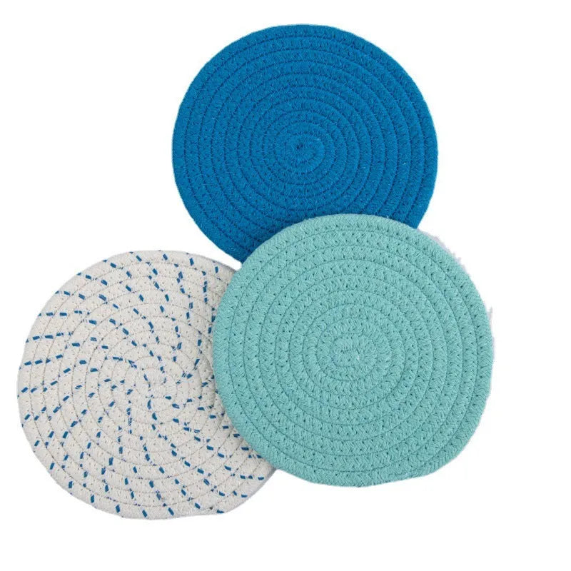Three round cotton cord coasters in coordinating colours on wooden table