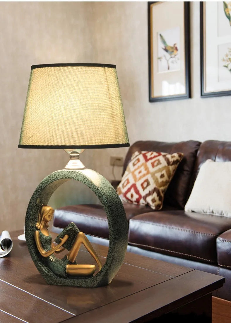 Blue resin reading girl table lamp with cloth shade on a table, 20x39.8cm