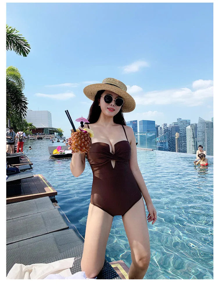 Women's solid colour spaghetti strap one-piece swimsuit with push-up design in white, pink, or brown.