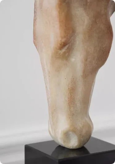 A tall, abstract white horse head sculpture with a carved surface texture on a shelf.