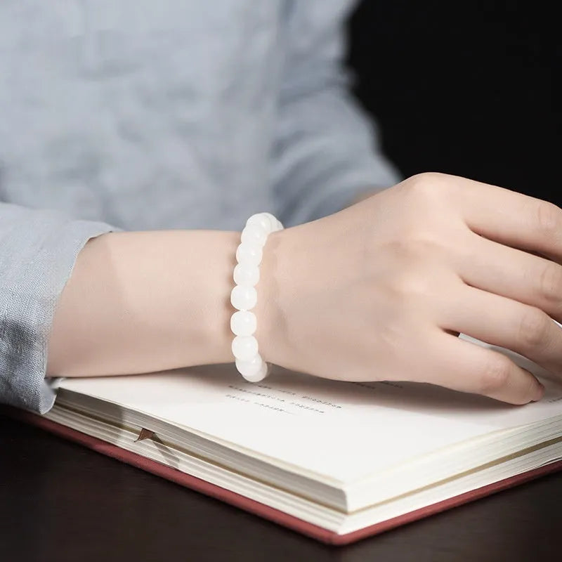 White Hetian jade barrel bead bracelet on a wrist, showing smooth beads in a unisex casual style.