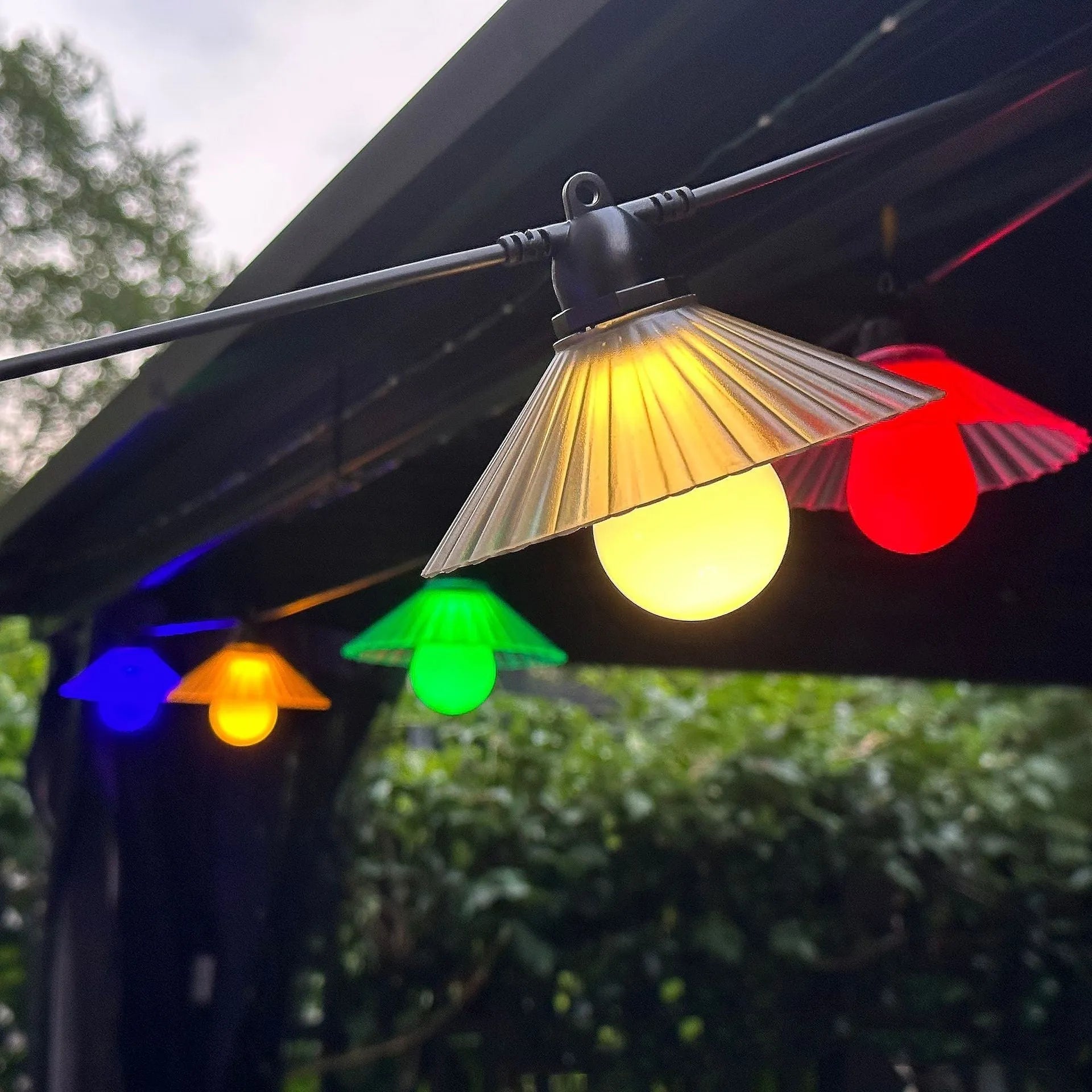 Outdoor LED string lights with flower-shaped white globes hung on a garden fence.
