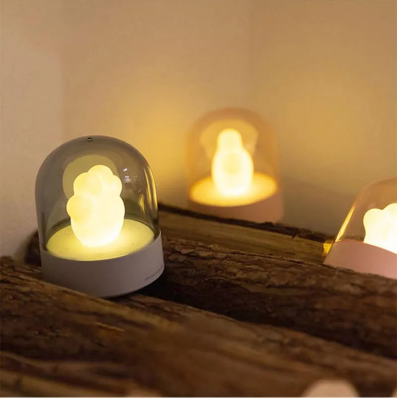 Grey and pink cat paw shaped night light with USB charging cable and musical rotation feature