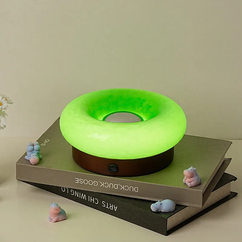 Donut-shaped touch table lamp in orange colour with three colour mode options on a desk
