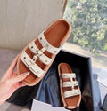 Women's white patent leather Roman style sandal slippers with sheepskin upper on a neutral background.