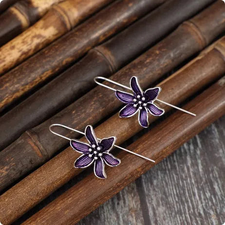 Close-up of a pair of purple flower-shaped alloy stud earrings with an electroplated finish.