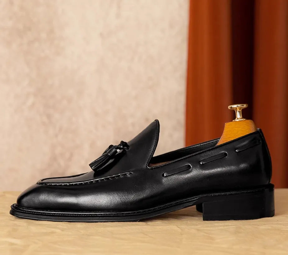 Men's black genuine leather slip-on loafers with fringe detail and rubber sole.