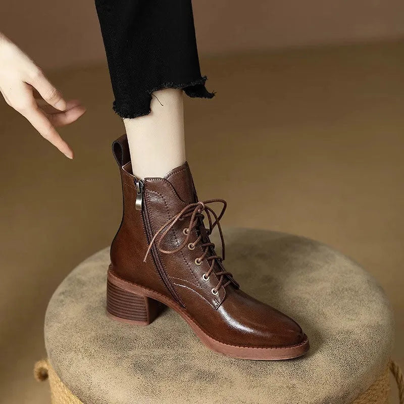 Women's black pointed-toe ankle boots with a low heel on a plain background.
