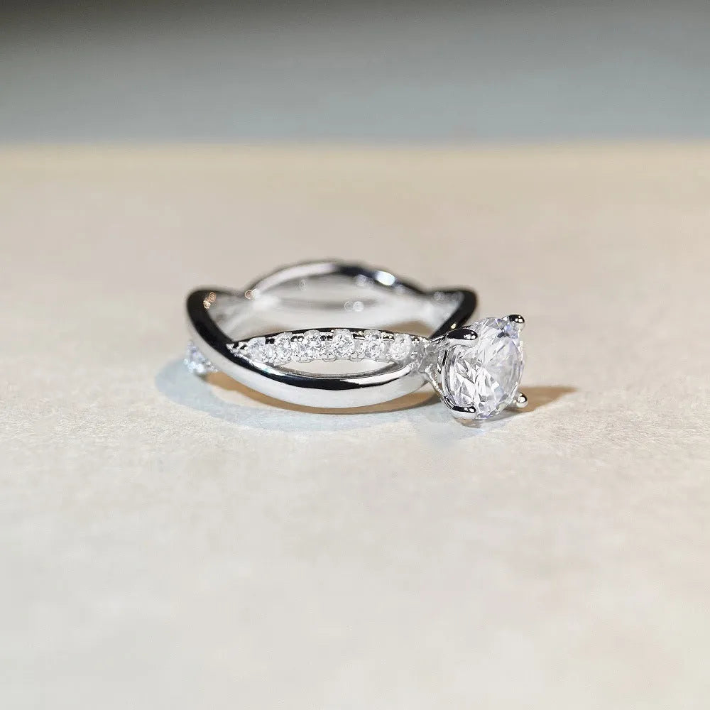 Silver geometric ring with a twisted band, a cross design, and a 1 karat moissanite in a four-claw setting.