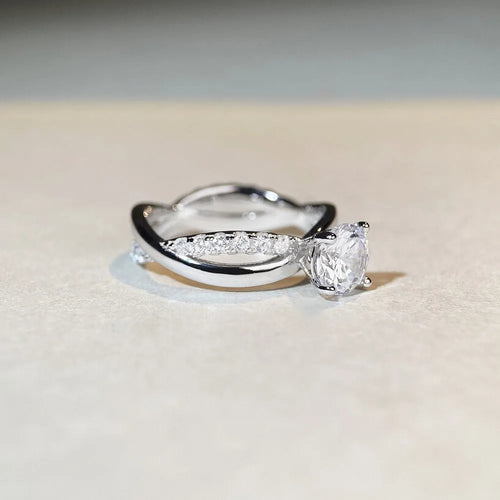 Silver geometric ring with a twisted band, a cross design, and a 1 karat moissanite in a four-claw setting.